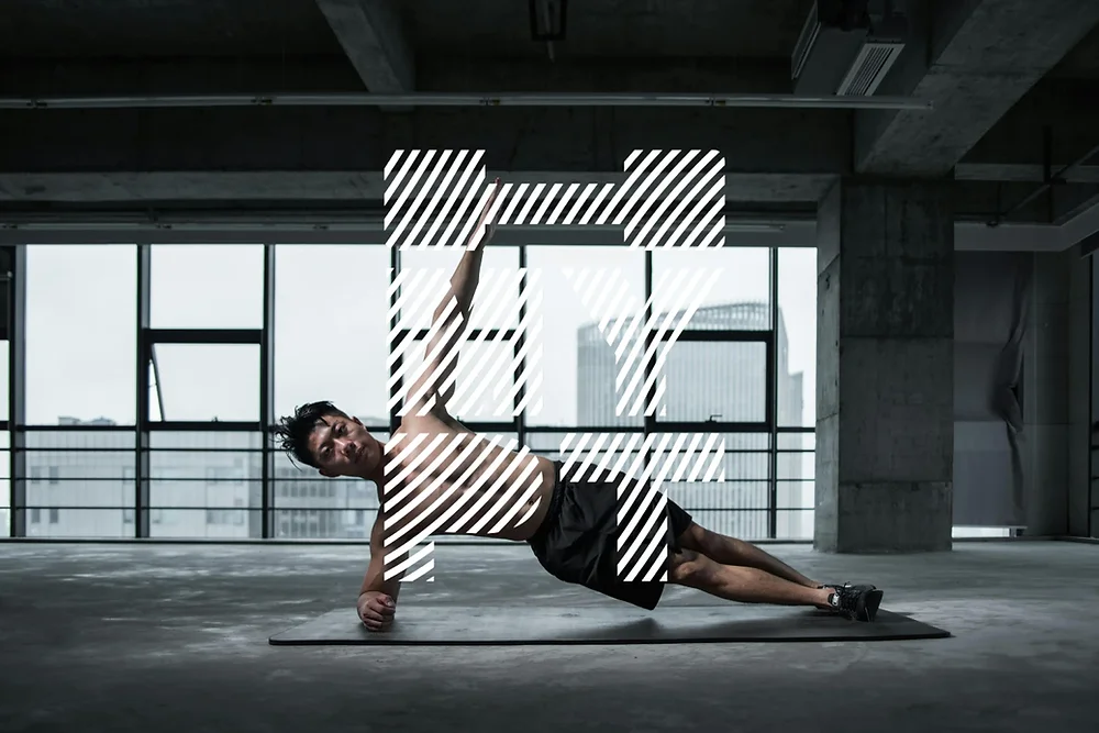 Entużjast avvanzat tal-fitness iwettaq eżerċizzju ta' side plank, li jenfasizza definizzjoni qawwija tal-muskoli addominali u stabbiltà f'ambjent modern ta' ġim.