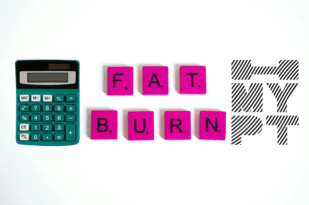 Fat Burning Calculator concept with a green calculator and pink Scrabble-style tiles spelling 'FAT BURN', representing weight loss and fitness planning by My Personal Trainer Malta.